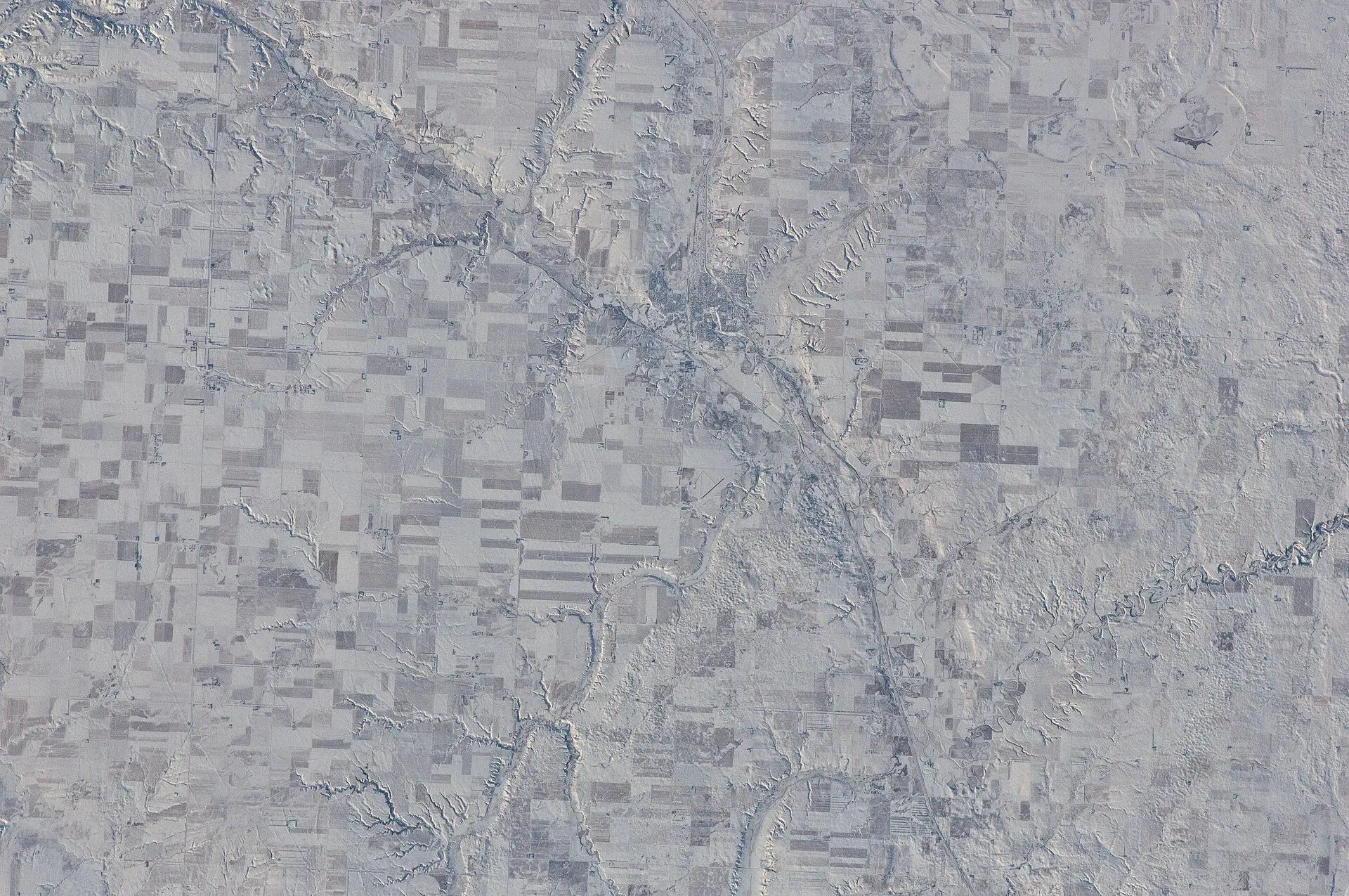 Aerial view of farmland and valley from space in winter