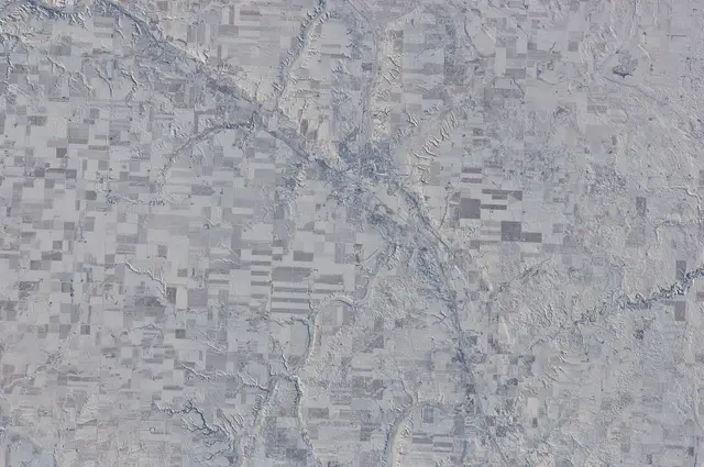 Aerial view of farmland and valley from space in winter